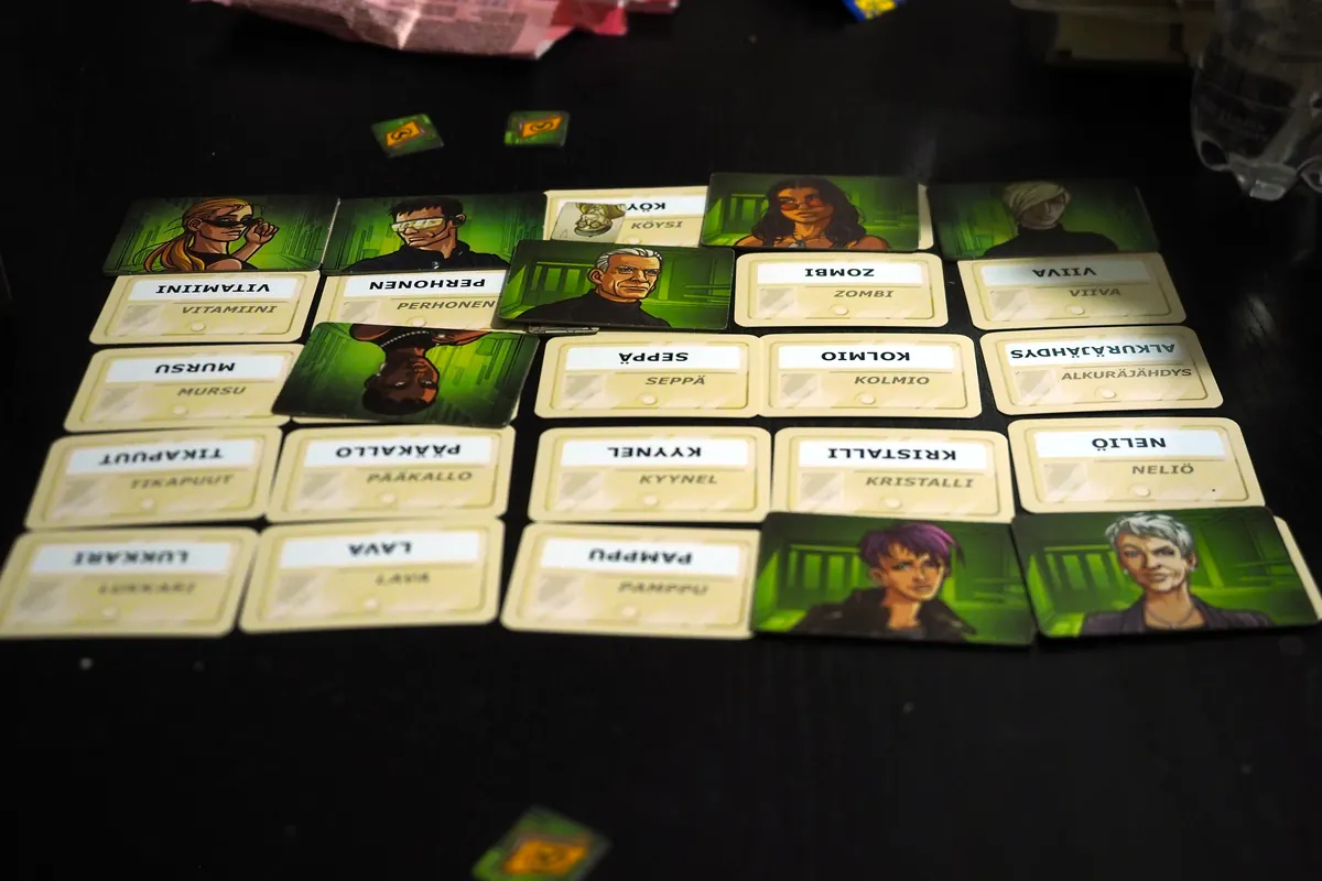 Codenames Duet mid-game: a five-by-five grid of word cards, several covered by green agent cards, on a dark table