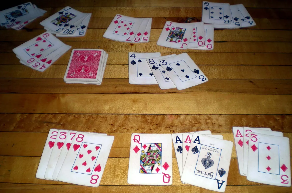Rummy melds of standard playing cards, runs and sets in hearts, spades and diamonds, laid out on a wooden table